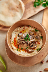 A Delicious Serving of Creamy Hummus Topped with Savory Mushrooms and Fresh Herbs, Perfect for Sharing and Enjoying with Pita Bread and Vegetables