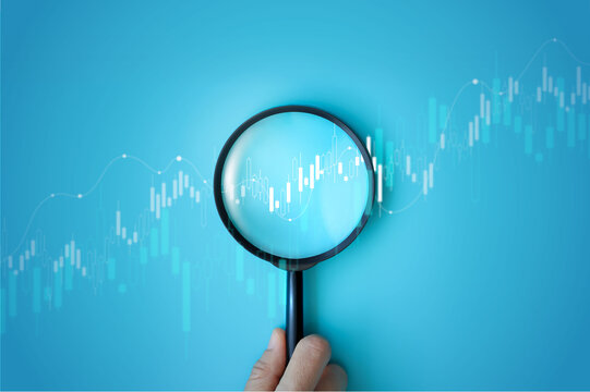 Hand holding magnifying glass analyzing digital financial stock chart. Data analysis, investment research, trading strategy, and financial market concept on blue background. business stock market.