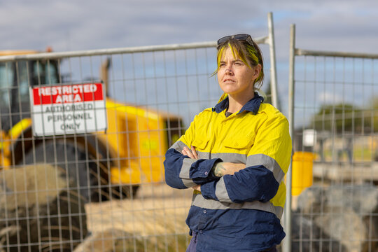 woman wearing hi-vis workwear standing with arms crossed in front of restricted area