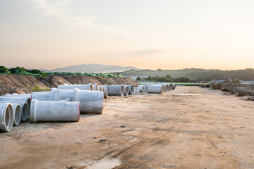 Expansive construction site with exposed earth and heavy machinery tracks. Surrounded by distant...