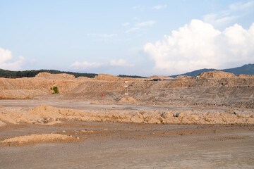 Expansive construction site with exposed earth and heavy machinery tracks. Surrounded by distant mountains, the scene captures early stages of land development and earthmoving operations.
