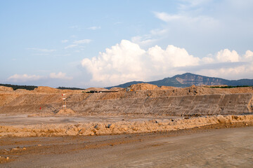 Expansive construction site with exposed earth and heavy machinery tracks. Surrounded by distant mountains, the scene captures early stages of land development and earthmoving operations.