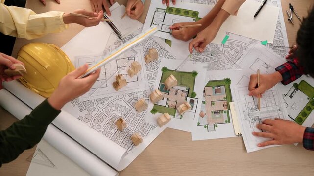 Architect and safety engineer discussion about building construction use blueprint on table with architectural document, measurement tool and wooden block scatter around at modern office. Delineation.