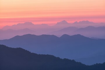 Fototapeta premium Stunning mountain ranges fade into a dreamy purple haze under a vibrant pink and orange pastel sky at dawn