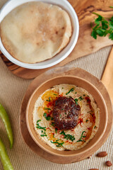 Delicious Middle Eastern Spread Featuring Flavorful Hummus with Spices and a Savory Meatball Accompanied by Pita Bread and Garnished with Fresh Herbs.