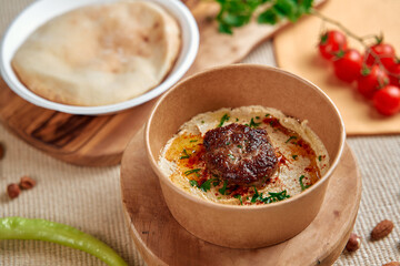 Delicious Hummus Bowl with Spiced Meatball Garnish and Accompaniments on Wooden Platter Surrounded by Fresh Ingredients and Flatbread