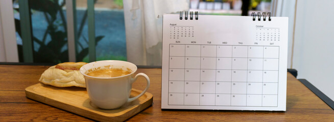 2025 calendar for planner to plan daily business appointment each day, month, and year on wooden table. Desktop calender hot coffee, and Vietnamese bread placed on wooden desk—calendar concept-banner