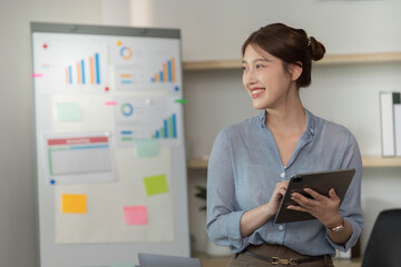 Professional woman analyzing data with tablet in modern office