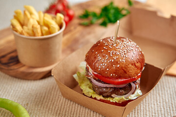 Delicious Gourmet Burger with Fresh Vegetables and Crispy Fries Served in a Rustic Box, Perfect for a Satisfying Meal Experience