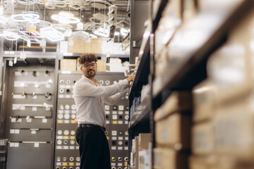 Fototapeta premium Professional Man Organizing Shelves in a Modern Lighting Store