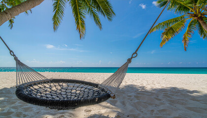 Horizontal photo of a tropical beach with white sand, turquoise water and blue sky. In the center of the composition is a wicker round hammock suspended from palm trees, the branches of which hang dow
