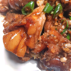 A close-up of a serving of savory pig's trotters (jokbal) garnished with fresh garlic and chili peppers.