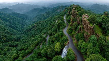 Winding road through lush mountain ranges, aerial view of a waterfall