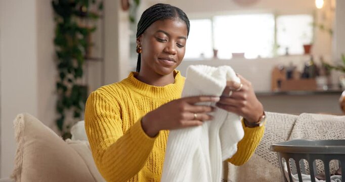 Home, fabric scent and black woman on sofa, folding laundry and satisfied in living room. Smelling, housekeeping and African person on couch, aroma and clean clothing with maintenance, pride or smile
