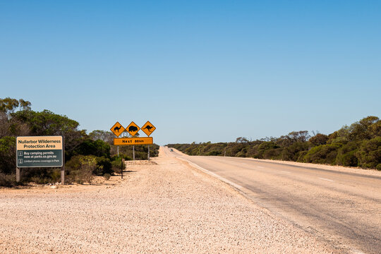 Road signs on side of open straight road of the Nullarbor in bright daylight