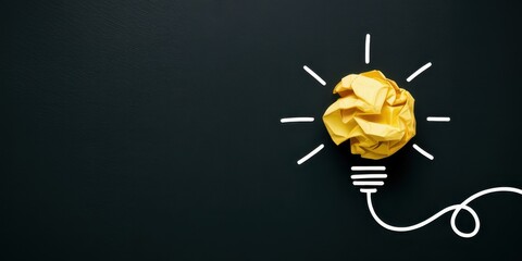 Creative idea concept with a crumpled yellow paper light bulb on a black background for innovation and inspiration