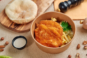 Crispy Fried Fish Fillet Served with Golden Fries and Fresh Salad Garnished with Herbs in a Rustic Bowl and Accompanied by a Tangy Sauce