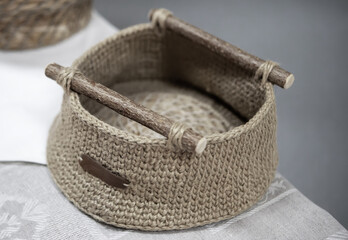 Handmade woven basket with wooden handles displayed on a woven textile background in a cozy artisan...