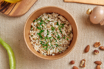 A Bowl of Wholesome Brown Rice Topped with Fresh Herbs, Nuts, and Accompanied by a Squeeze of Lime on a Rustic Table Setting
