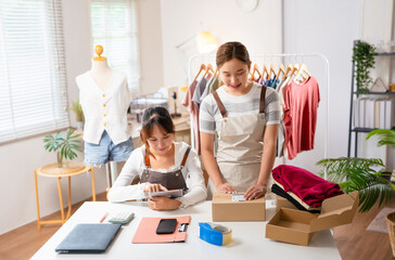 Obraz premium Asian partner startup small business owner packing goods for delivery to clients.