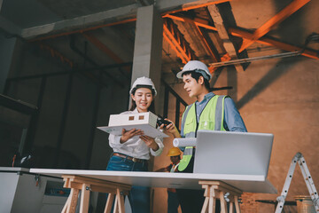 Construction manager and engineer dressed in orange work vests and hard helmets explore construction documentation on the building site near the steel frames