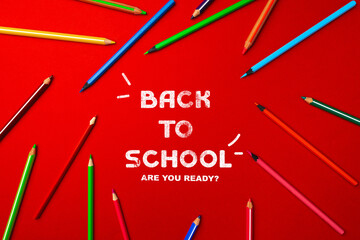 Colorful pencils arranged on a vibrant red background with back to school message for students preparing for new academic year