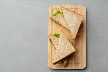 Delicious whole grain sandwiches with fresh lettuce on a wooden cutting board