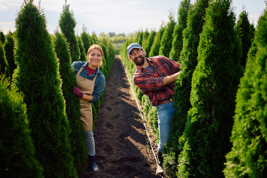 Happy workers having fun while working at tree nursery and looking at camera.