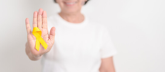 Elderly with Yellow Ribbon for concept of yellow September, Suicide prevention day, Childhood, July Sarcoma, bone and bladder cancer Awareness month, support survivor. Healthcare and World Cancer day