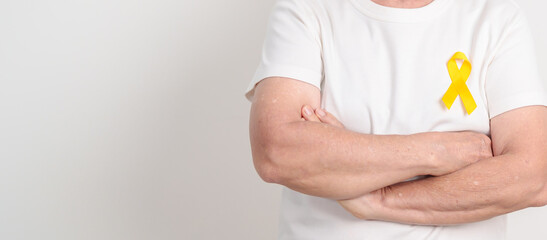 Elderly with Yellow Ribbon for concept of yellow September, Suicide prevention day, Childhood, July Sarcoma, bone and bladder cancer Awareness month, support survivor. Healthcare and World Cancer day