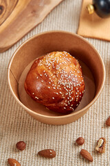 Deliciously Golden Brown Bread Roll Topped with Sesame Seeds Garnished with Almonds on Natural Textured Surface for Culinary Delight
