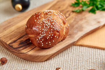 Freshly Baked Sesame-Topped Bread On A Rustic Wooden Board Surrounded By Natural Elements Such As Herbs And Nuts, Perfect For Any Meal or Gathering