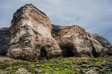 Cliff caves on coastline with rocky beach