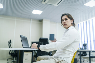 Man reviews analytics with coffee at bright office space.