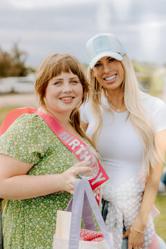 Women celebrating birthday outdoors with smiles and wine