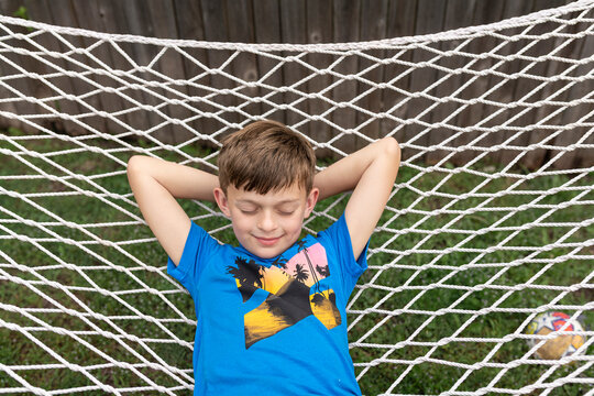 Boy  relaxing on backyard hammock with closed eyes