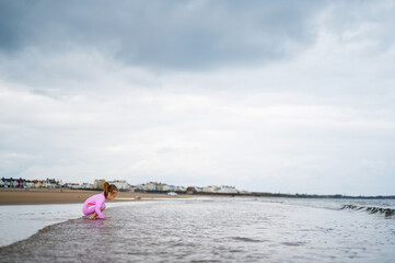 Little girl playing at the northern english seaside, cloudy day