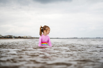 Little girl playing at the northern english seaside, cloudy day