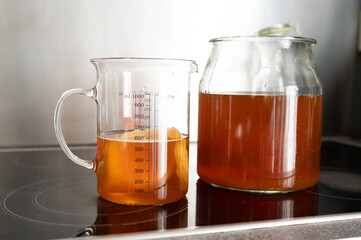 Glass pitcher and jar of homemade kombucha in kitchen setting