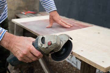 Caucasian male using angle grinder to cut wood on workbench