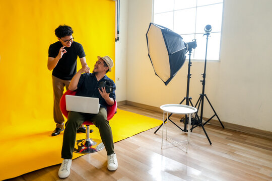 Photographer And Model Share A Laugh While Reviewing Photos On A Laptop During A Fun Studio Session