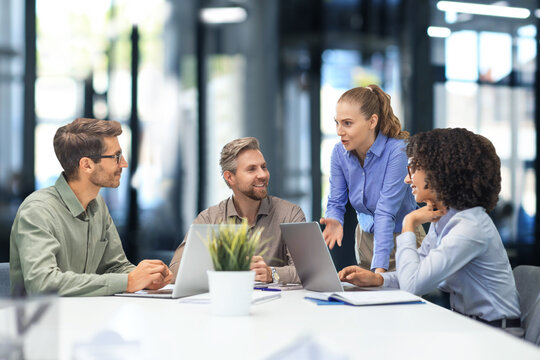 Happy four business people executive team working at laptop having discussion at office meeting showing financial project