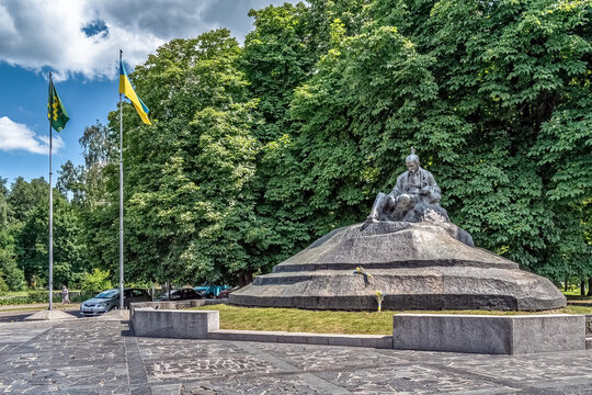 Monument to Ukrainian poet Taras Shevchenko in central park with Ukrainian flag and lush greenery in Romny. Historic memorial statue on stone pedestal. Romny, Ukraine - June 29, 2024