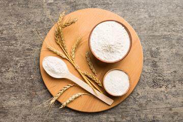 Flat lay of Wheat flour in wooden bowl with wheat spikelets on colored background. world wheat...