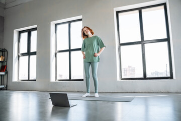 Fototapeta premium Woman practicing yoga in an urban studio with large windows during daytime