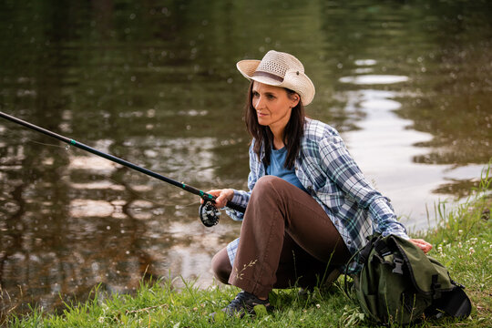 woman in a straw hat  fishing on the bank of a serene lake.