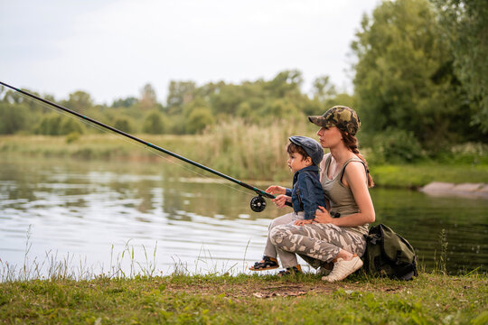 young mother fishing on the lake with her little son