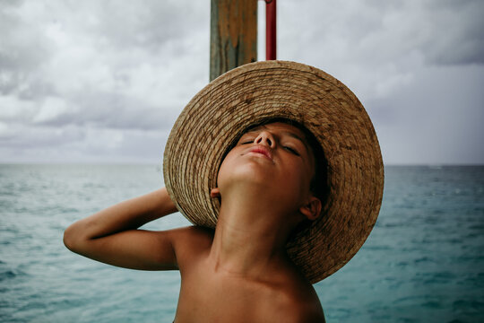 Boy wearing a beach hat while the storm approaches the beach.