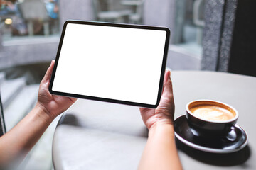Mockup image of a woman holding digital tablet with blank white desktop screen in cafe