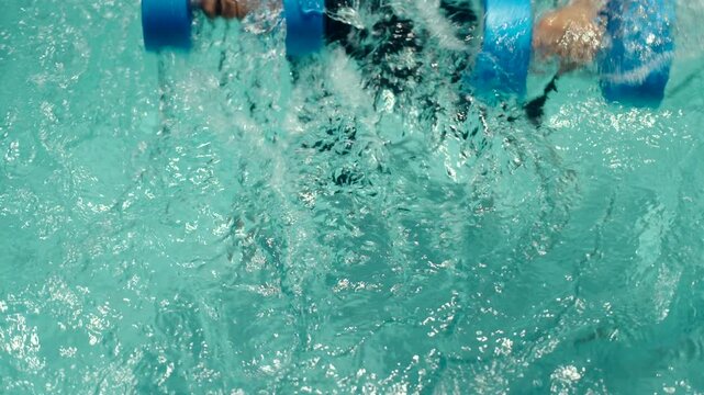 Man in a swim cap and rash guard relaxes and exercises in the pool, holding blue aquatic dumbbells, highlighting hydrotherapy, water fitness, and refreshing aquatic workouts.